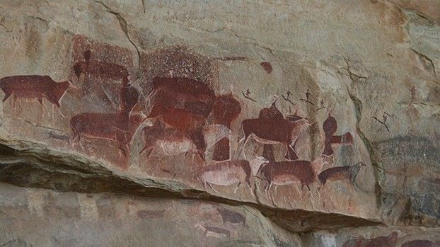 Rote Felszeichnungen von Antilopen und Menschen an einer Felswand
