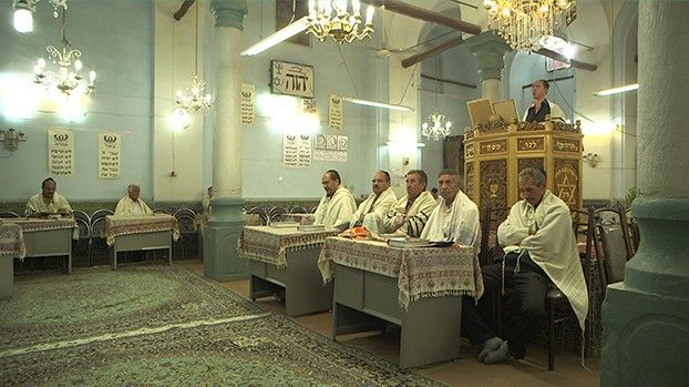 Männer mit Gebetsschals in einer Synagoge mit Kronleuchtern