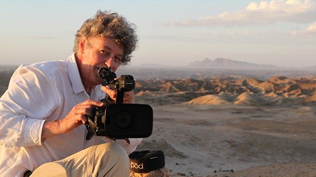 Rüdiger Lorenz mit Videokamera vor einer Hügellandschaft