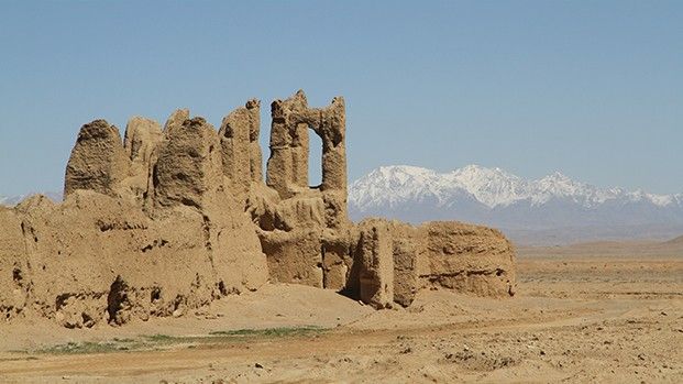 Lehmruine einer Karawanserei in der Steppe vor schneebedeckten Bergen