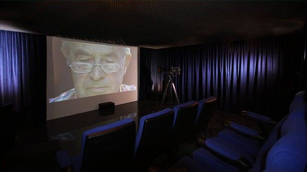 Vorführraum mit Leinwand und blauen Kinosesseln