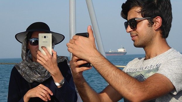 Junge Frau und junger Mann fotografieren mit Smartphones an Deck einer Fähre