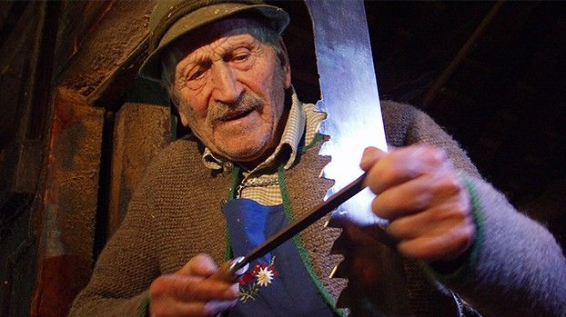 Alter Mann mit Hut schärft ein Sägeblatt